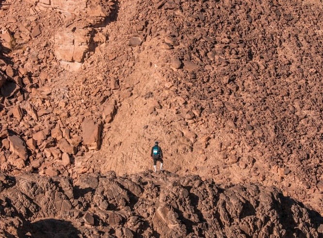 A Runner standing on top of a mountain having a break