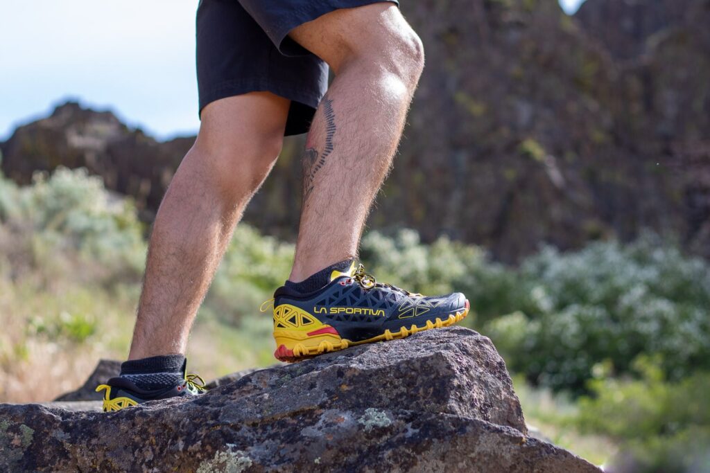 Ultramarathon runner showing the shoe and standing on top of a rock